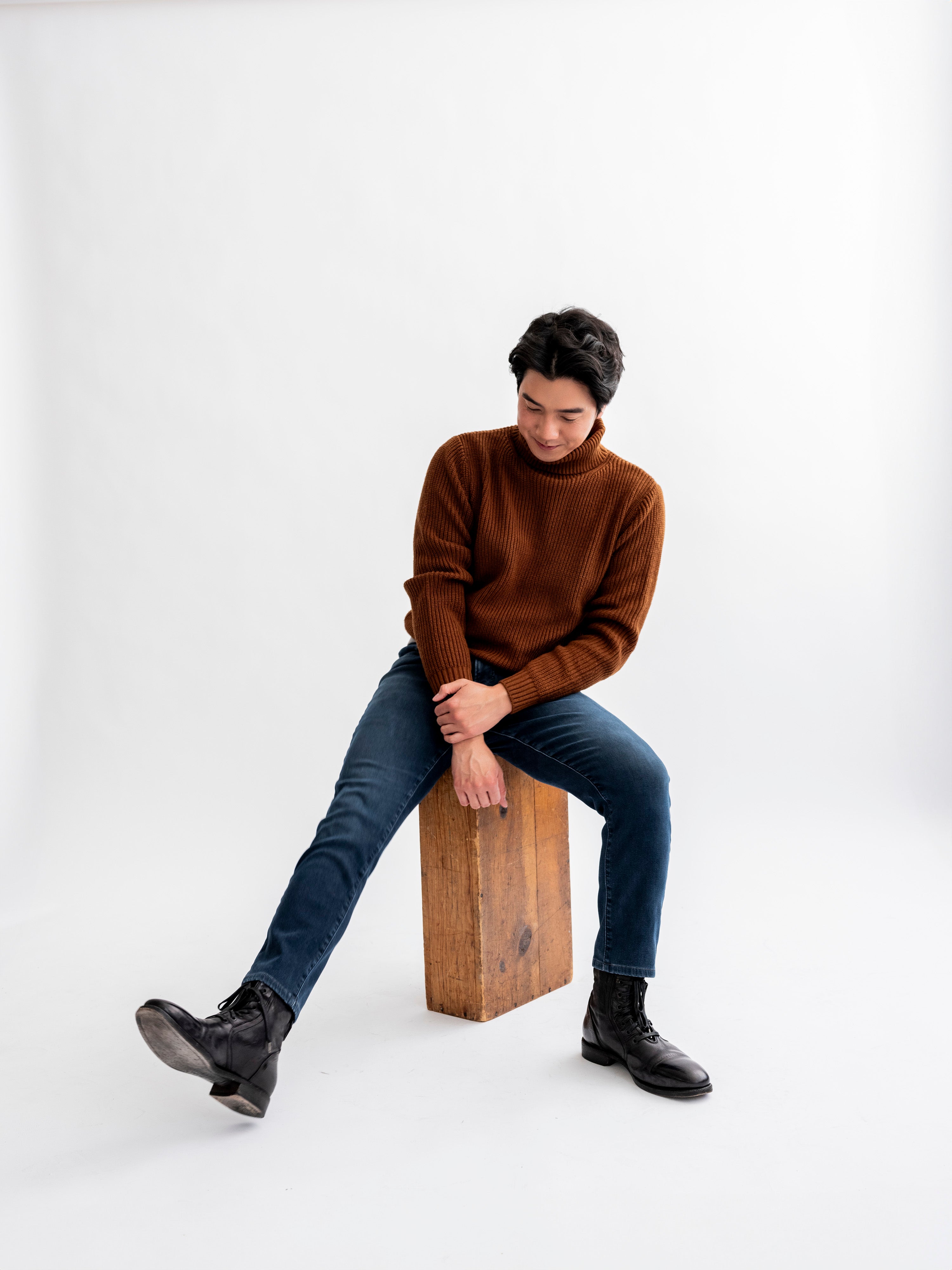 Man in white room sitting on apple box