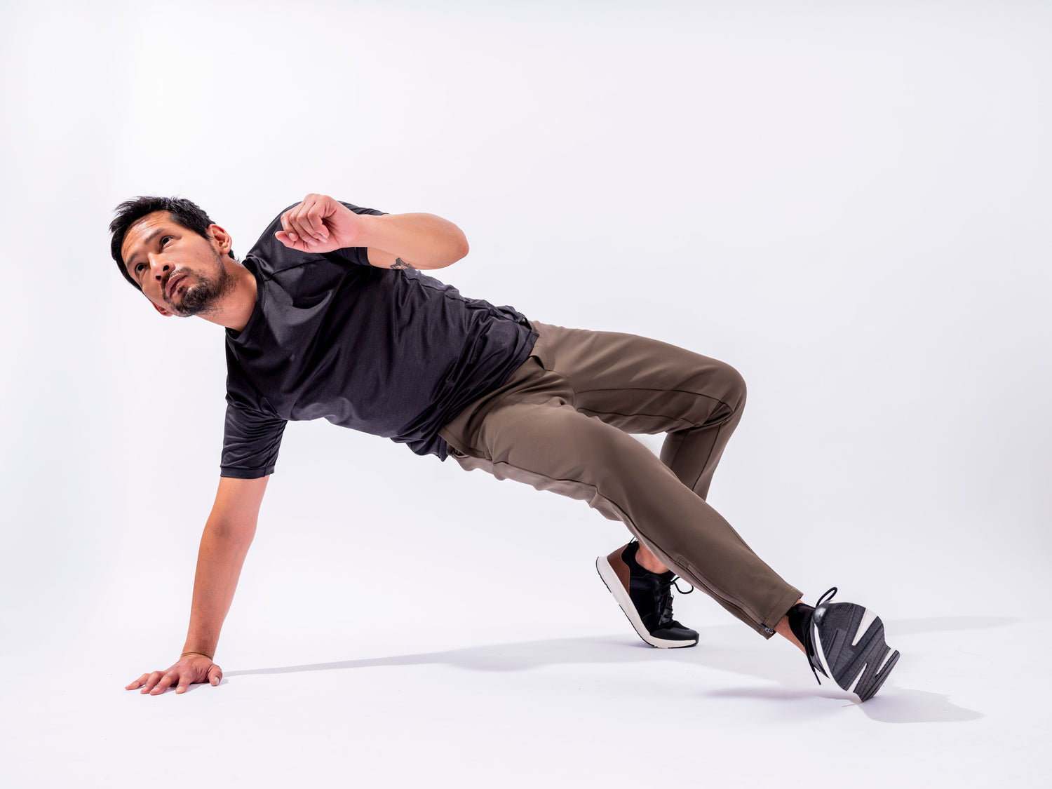 Man in white room with one hand on the floor athletically kicking wearing the Andy Joggers