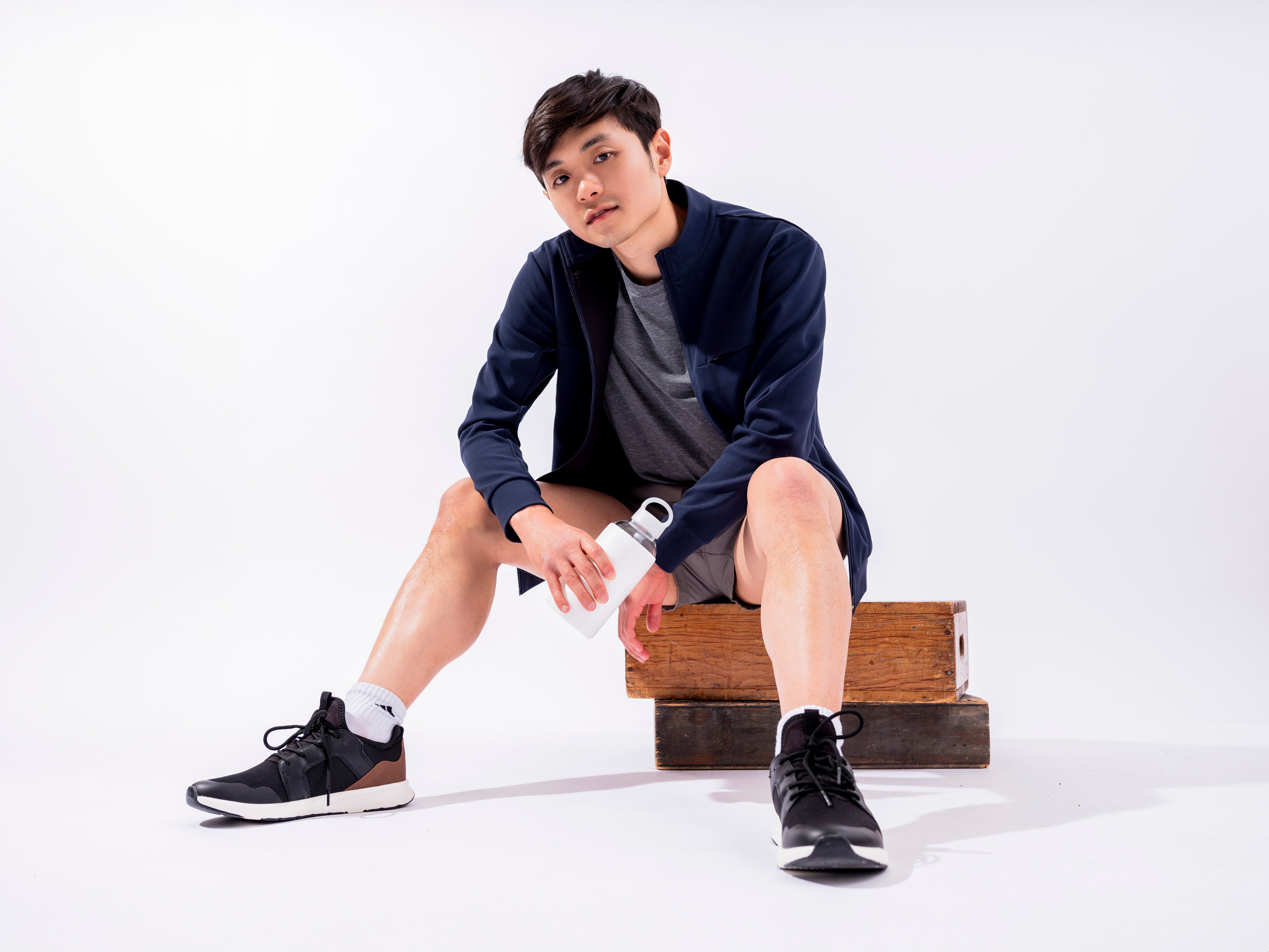 Man sitting on apple boxes in white room wearing the Hunter Jacket