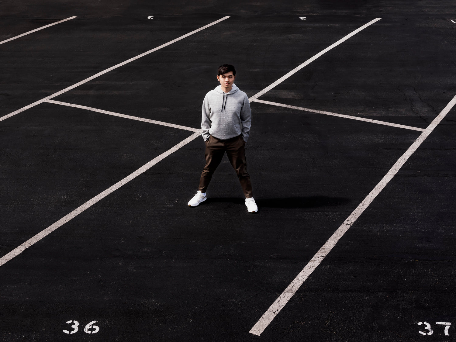 Man standing in empty parking spots staring to camera wearing the Andy Joggers