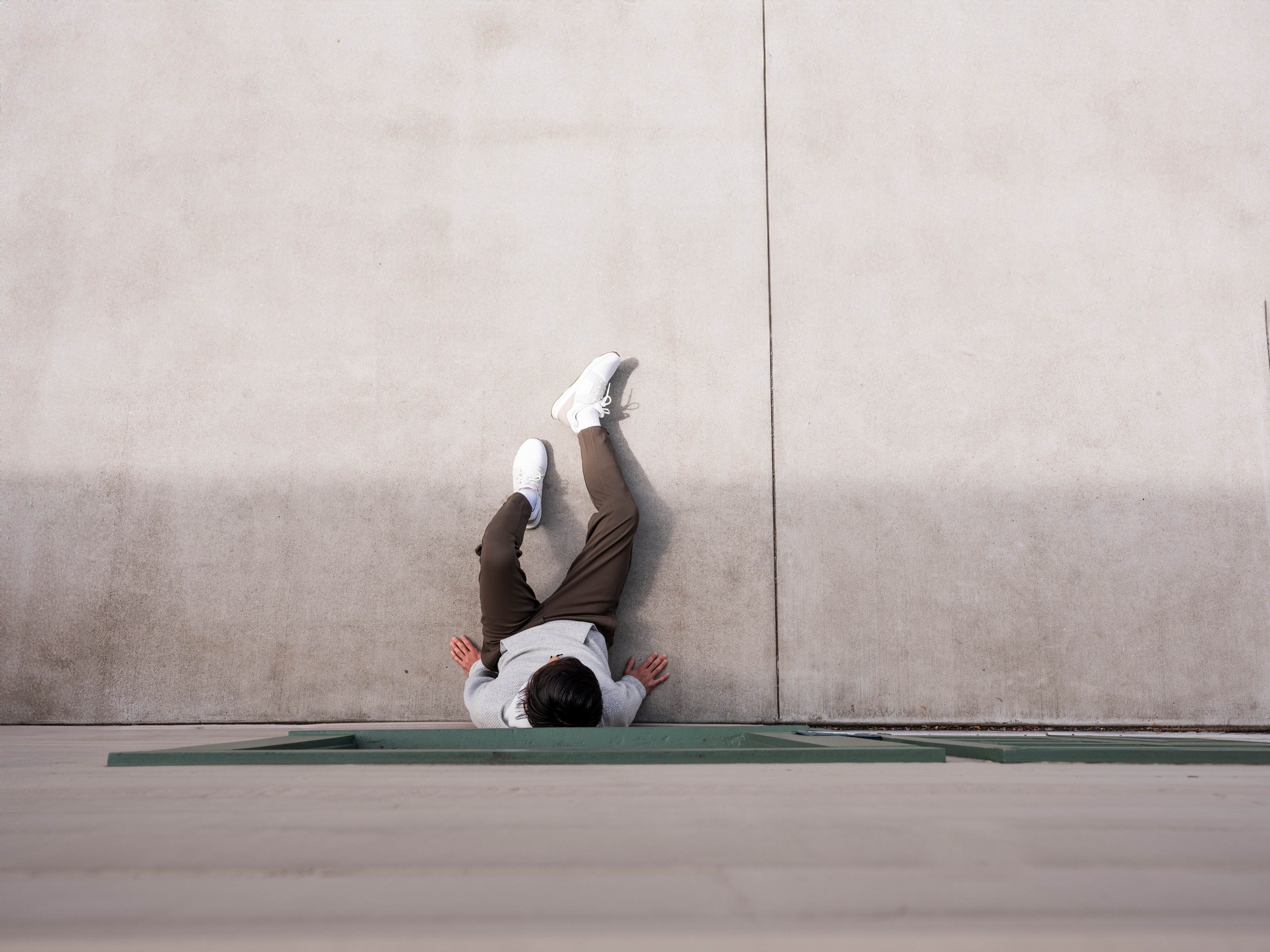 Overhead view of man sitting against exterior wall wearing the Andy Joggers