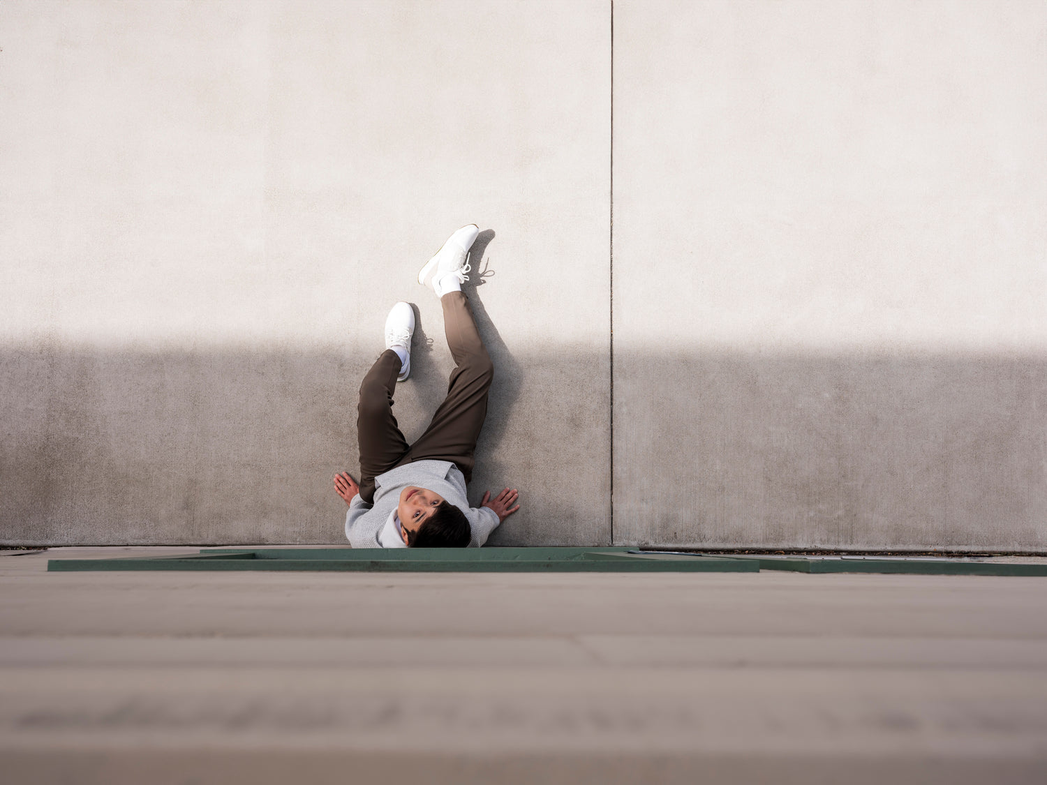 Downward shot of man sitting against exterior wall staring to camera wearing the Andy Joggers