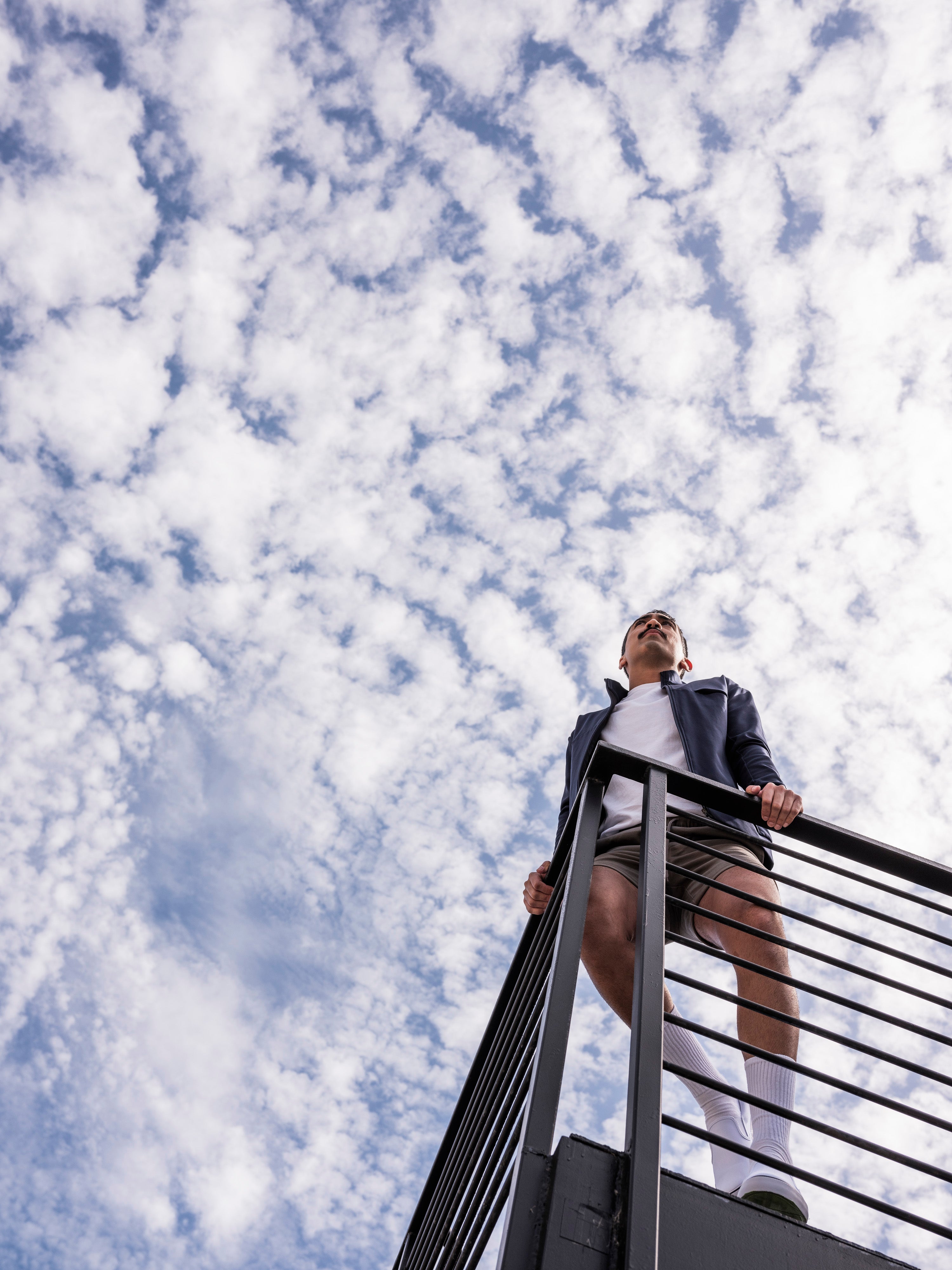 skyward view of man leaning against railing wearing the Hunter Jacket