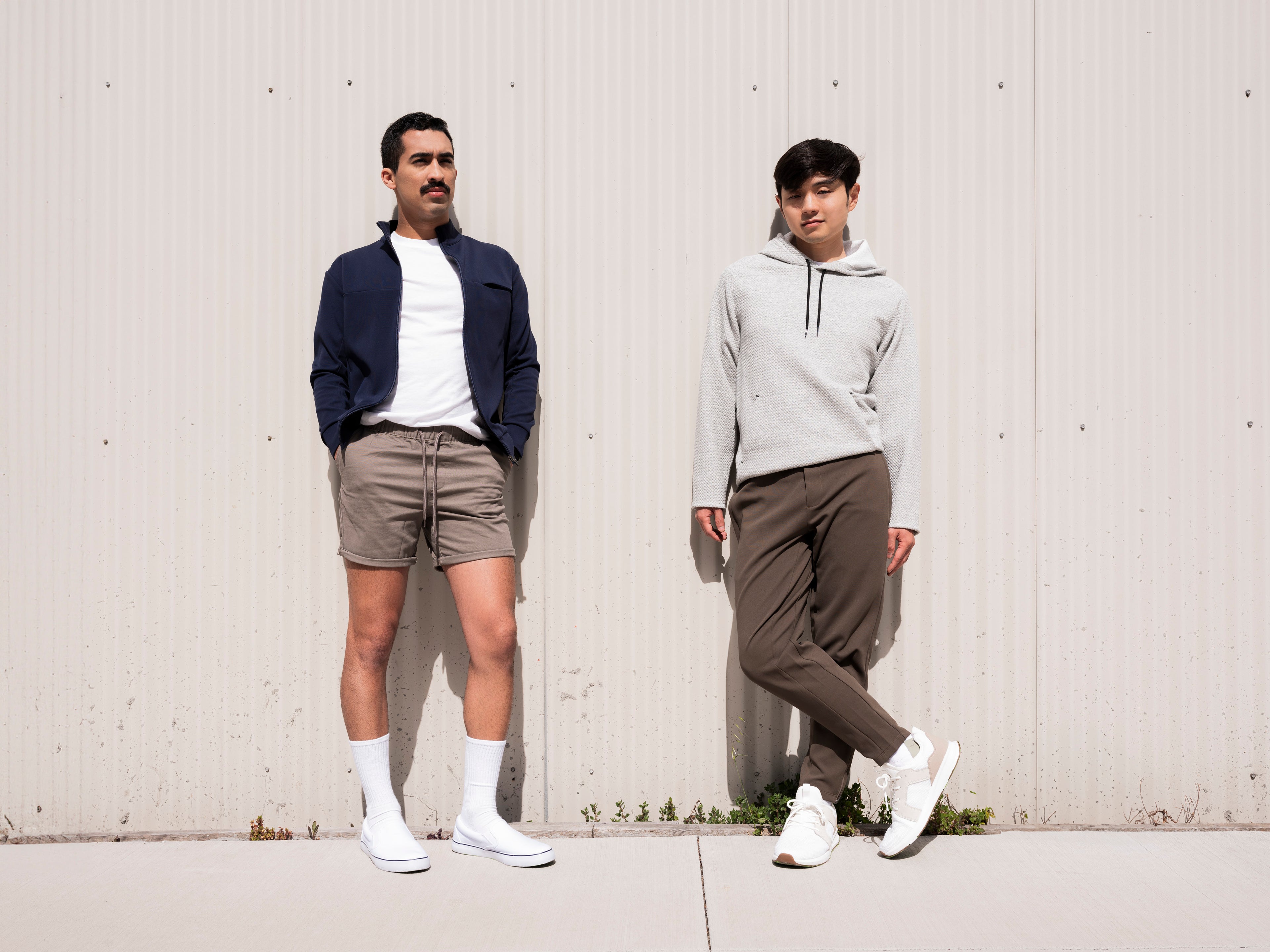 Two men leaning against exterior building wall wearing the Andy Joggers and Hunter Jacket